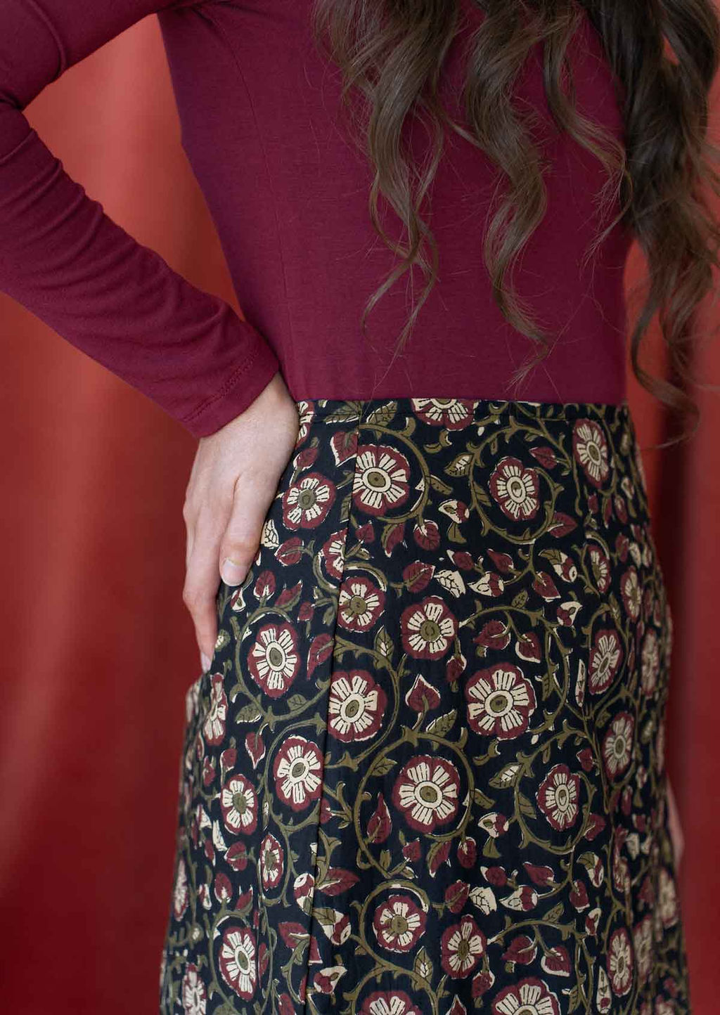 Close up image of a model wearing a reversible cotton skirt with bold floral print on black base on this side.