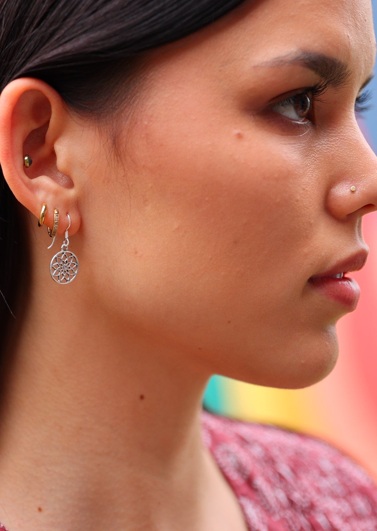 Woman wears silver sacred flower earring with wire hook