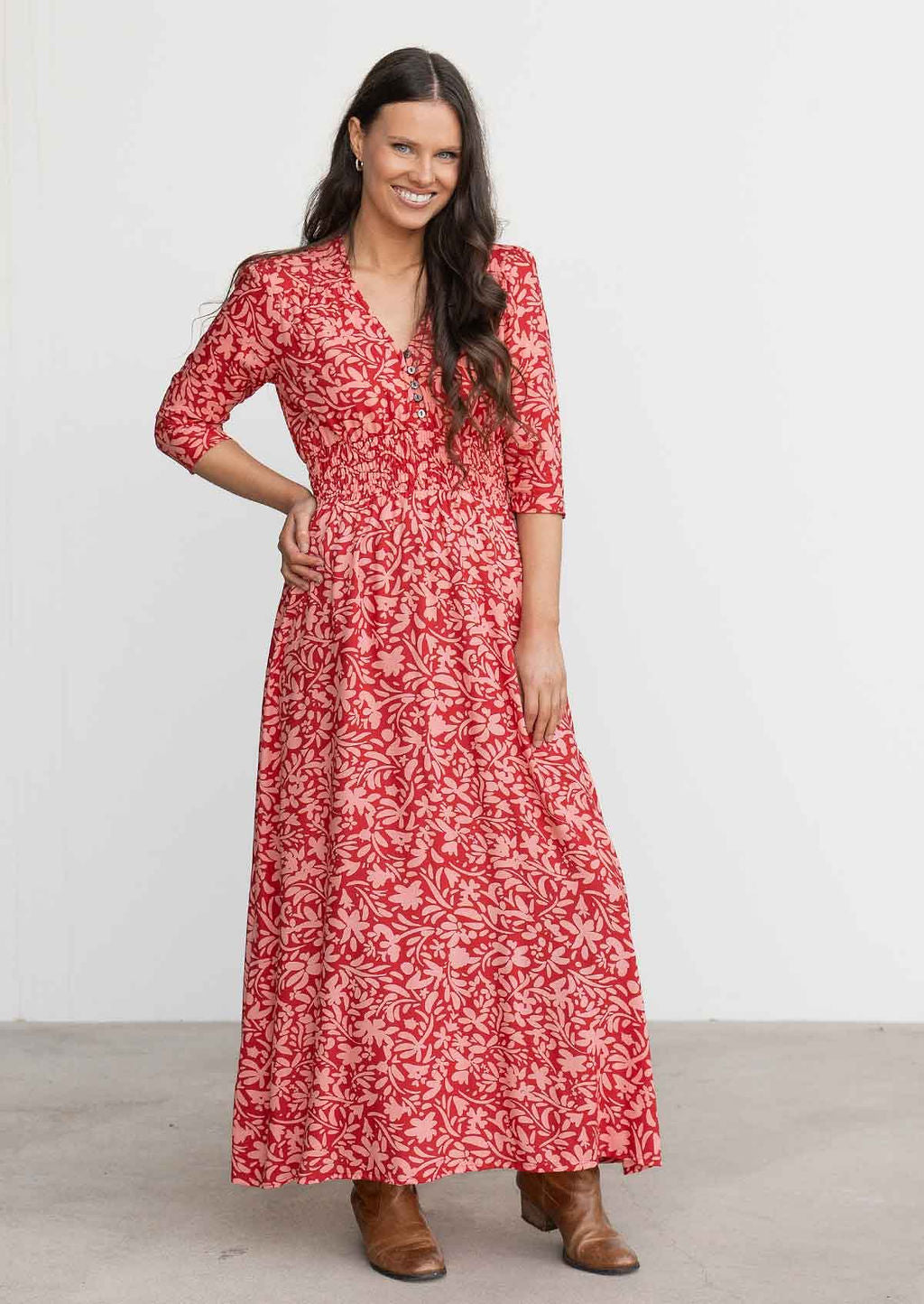 Model wears red and coral floral print rayon maxi dress with buttoned bodice and 3/4 sleeves