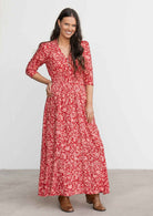 Model wears red and coral floral print rayon maxi dress with buttoned bodice and 3/4 sleeves