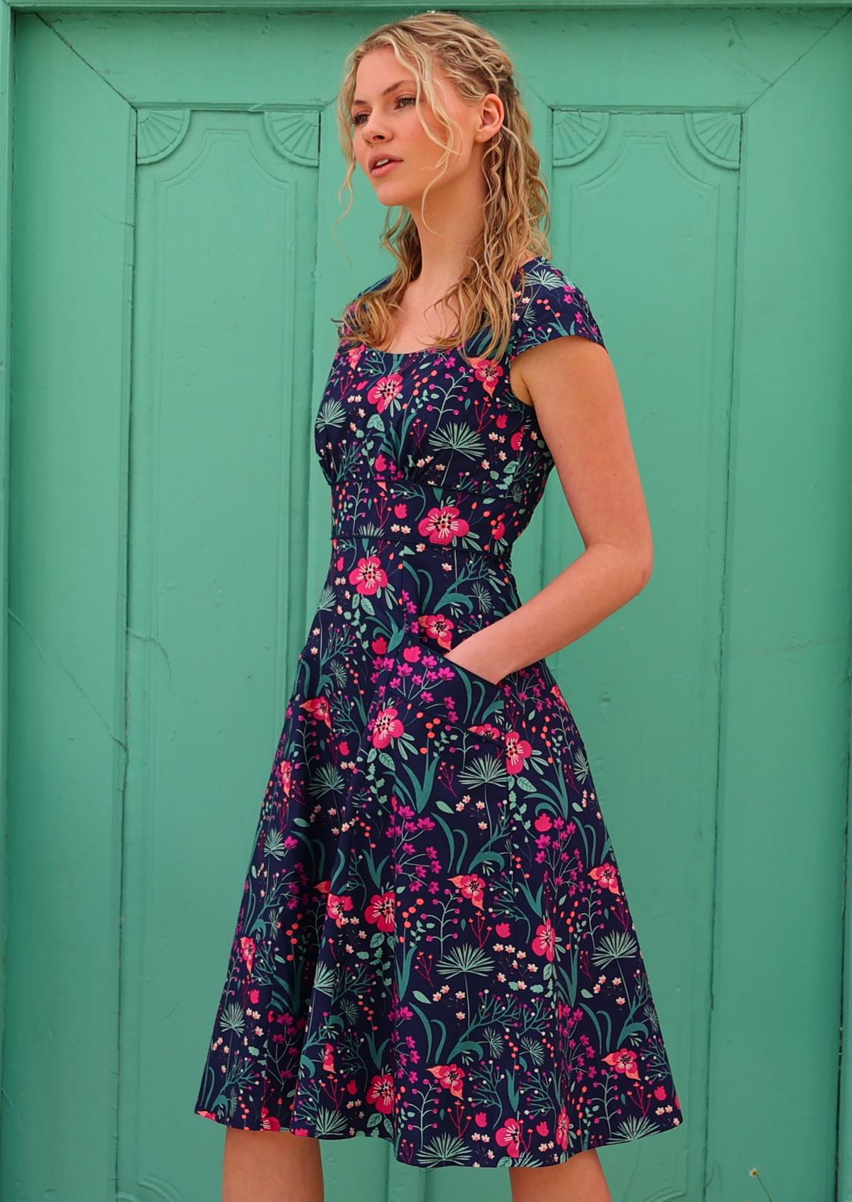 woman in retro inspired Scarlett Dress Dianthus in a   navy, purple, pink and aqua floral print on 100% cotton
