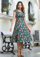 Model wears 100% cotton green floral printed dress with round neck, fitted waist and piped details across the waist and pockets.
