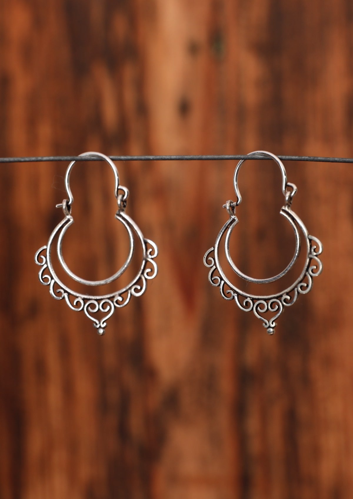 92.5% silver boho style earrings with curves sitting on a wire for display.