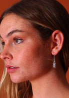 Woman wears silver filigree teardrop earrings with wire hooks
