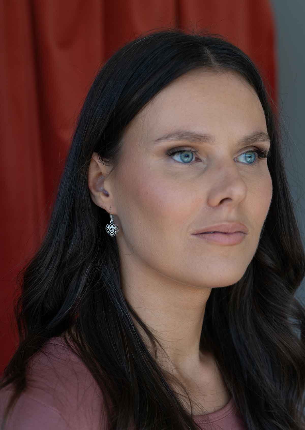 woman wearing large silver filigree heart earrings