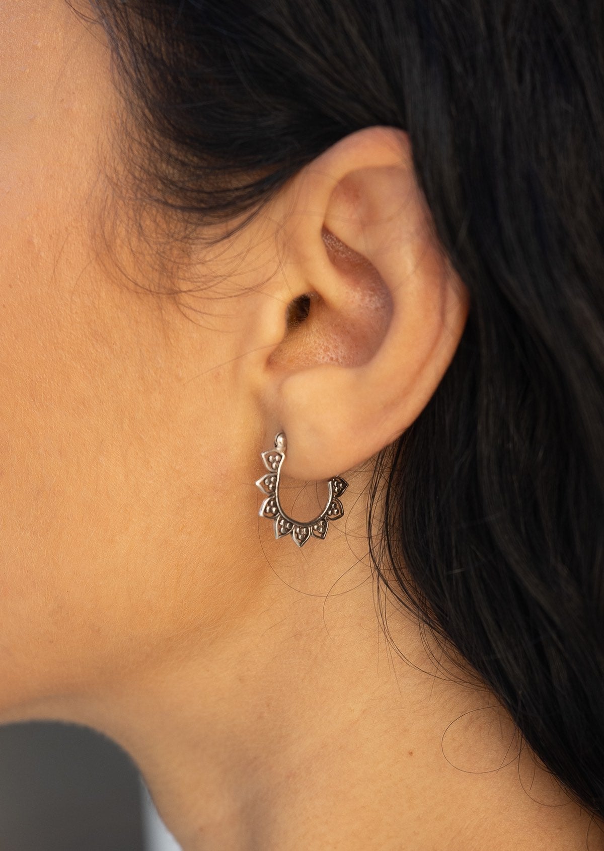 Close-up of a sterling silver petal adorned hoop earring with a clip closure
