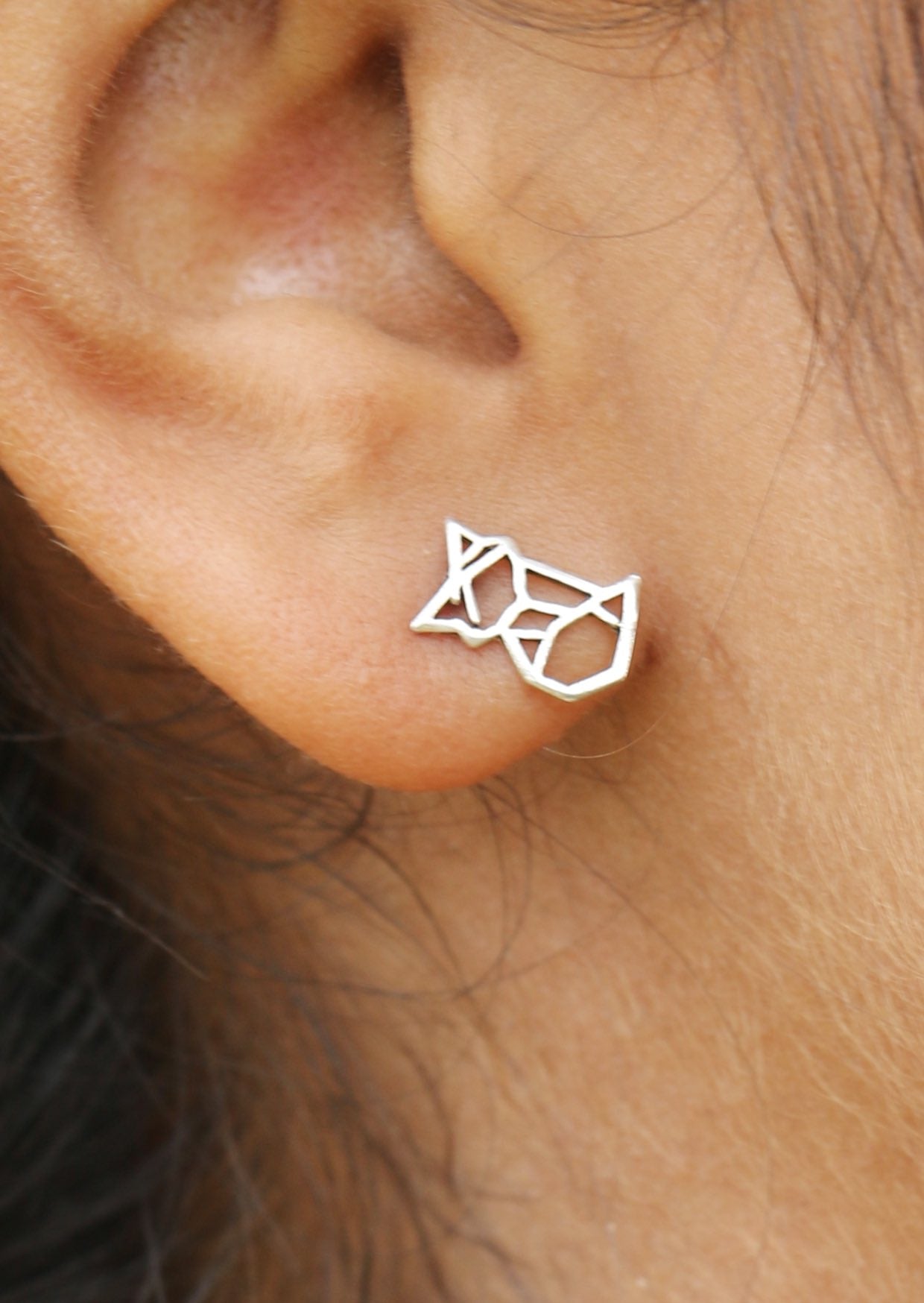 Sterling silver geometric fox studs with butterfly backs displayed on a woman's ear