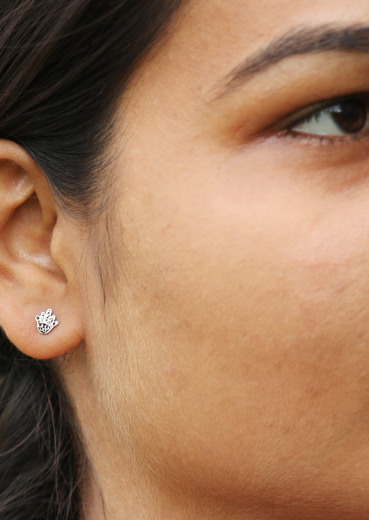 Woman wearing sterling silver Hand of Fatima studs with delicate lacework