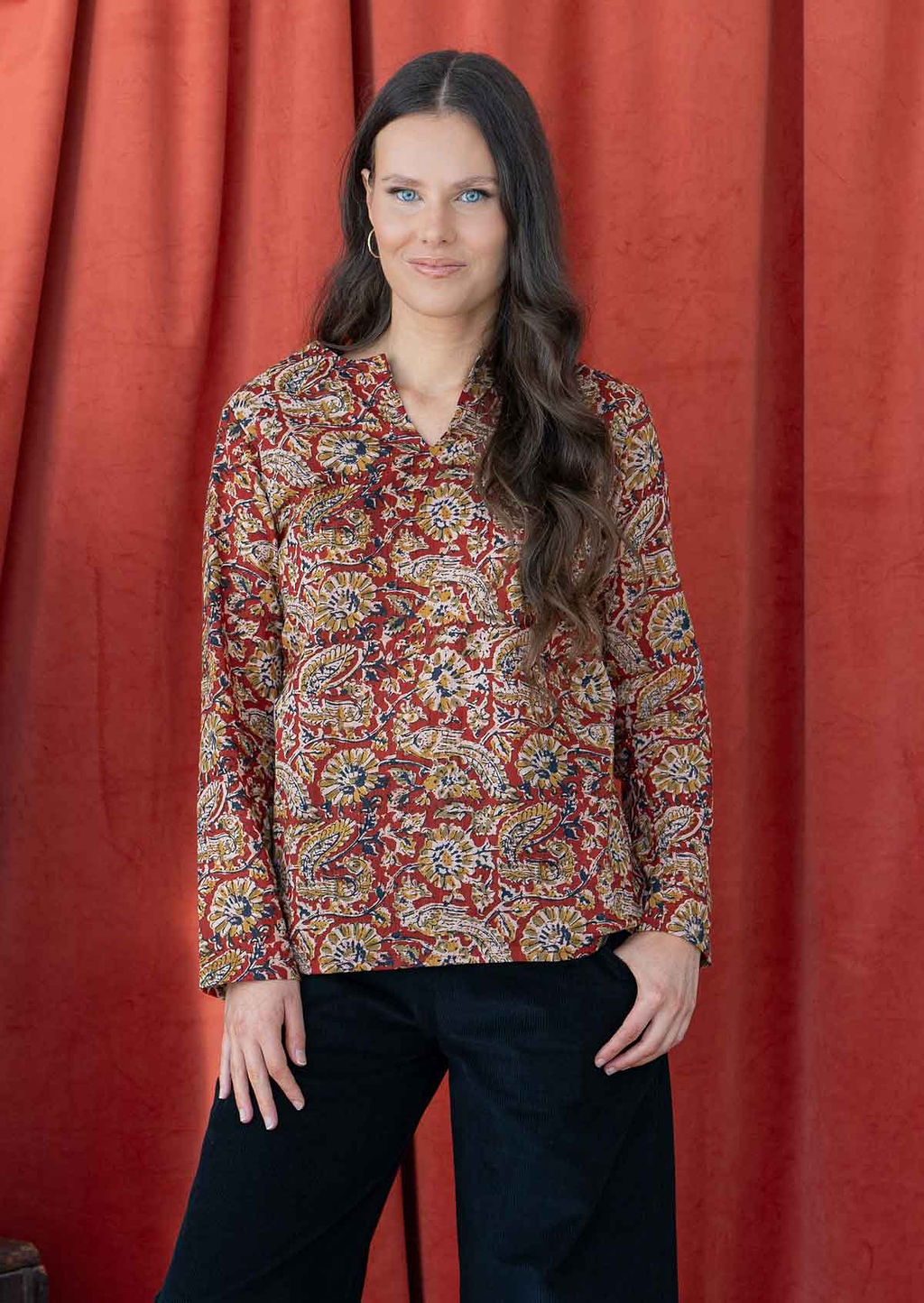 Model wears lightweight, cotton long sleeve top with keyhole cutout, in a earthy red based floral print.