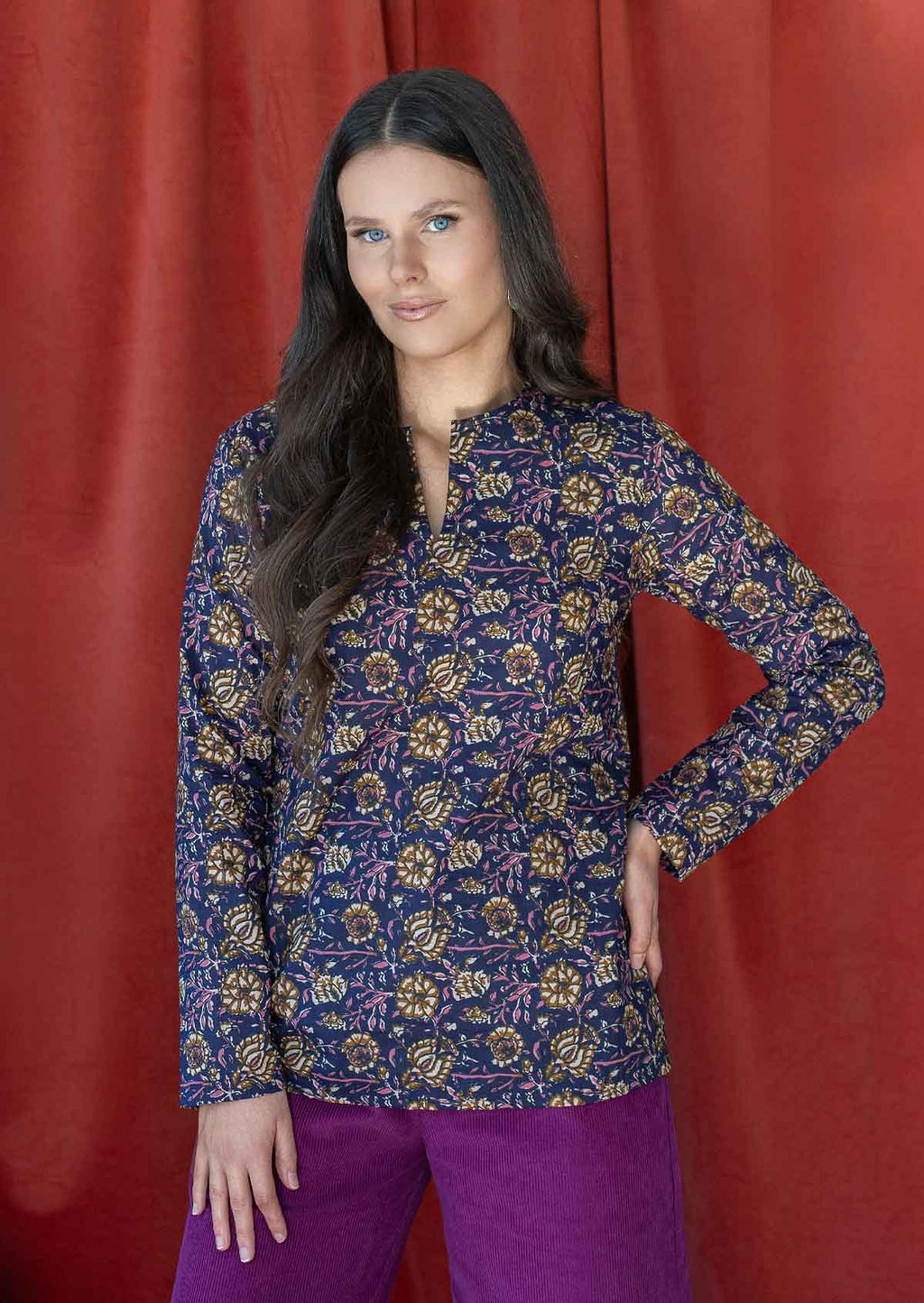Model wearing a 100% cotton floral printed dark purple top with long sleeves and V cutout neckline.