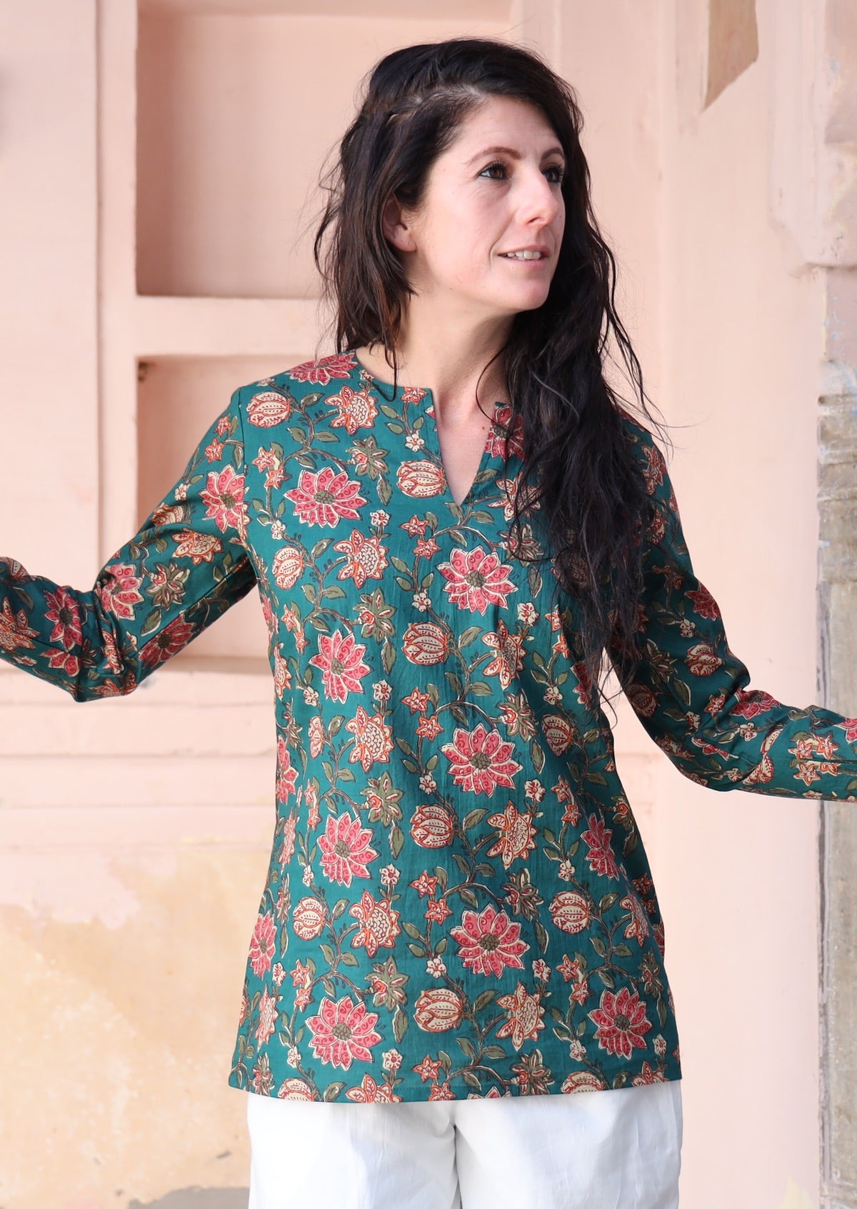 Woman wears cotton long sleeve top with keyhole V-cutout, in a green based floral print