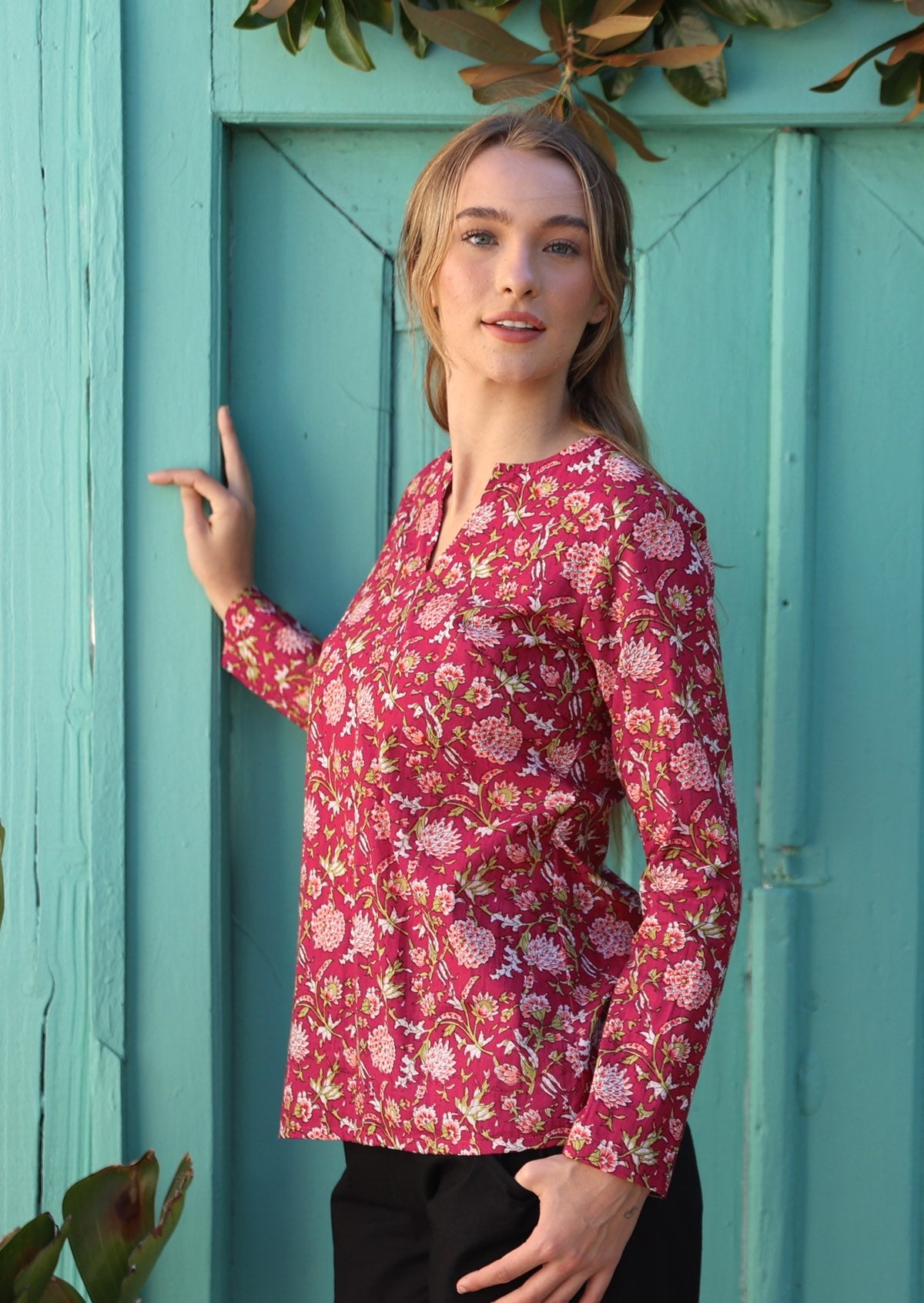 Model wears bright red cranberry based cotton top with pink floral print and long sleeves.