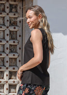 Woman posing in a 100% cotton sleeveless black top with trim detailing and bust darts