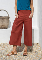 Person wearing rust 3/4 length. wide leg pants and a blue sleeveless top