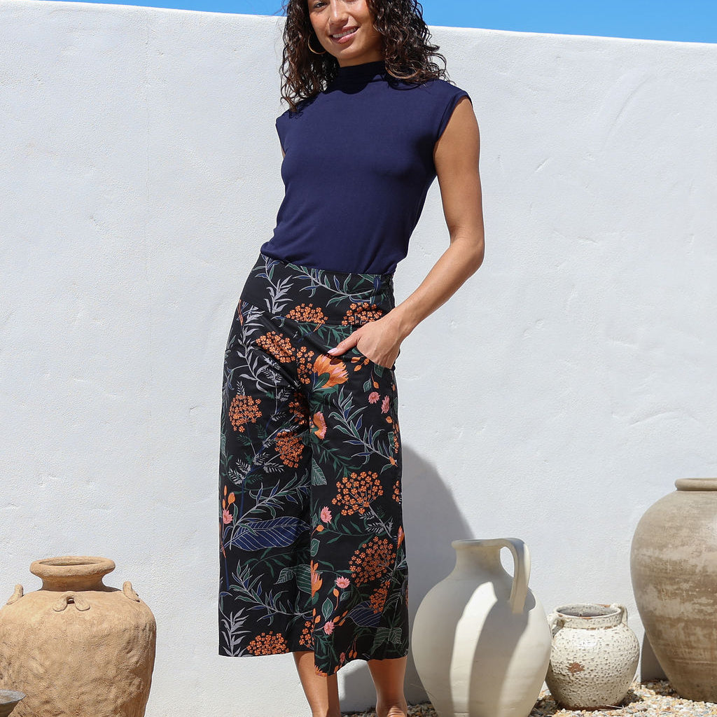 Woman wearing a navy basic rayon top and black botanical print wide leg 3/4 cotton pants with side zipper and pockets