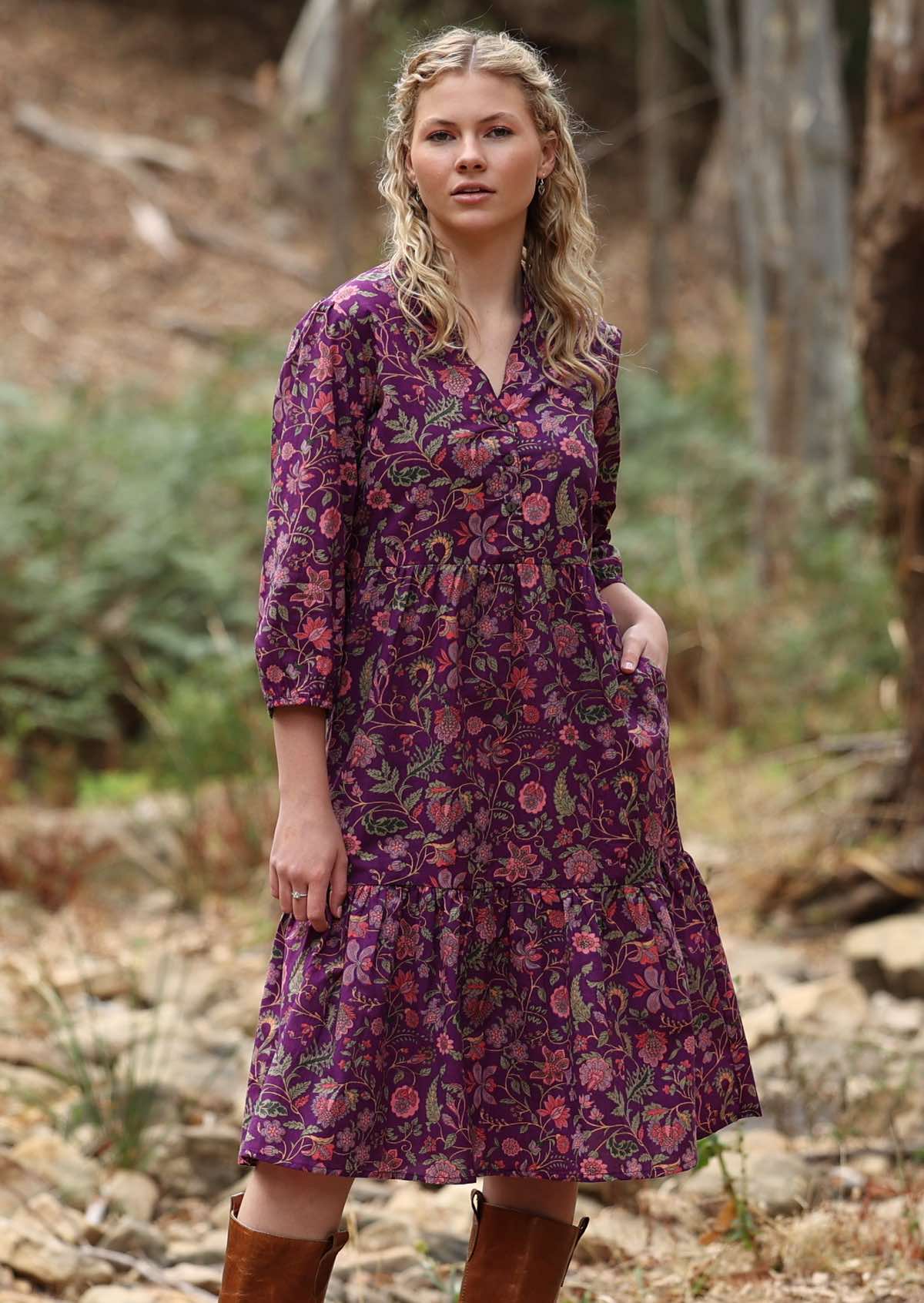 Woman wears midi length purple floral print boho dress with hand in pocket