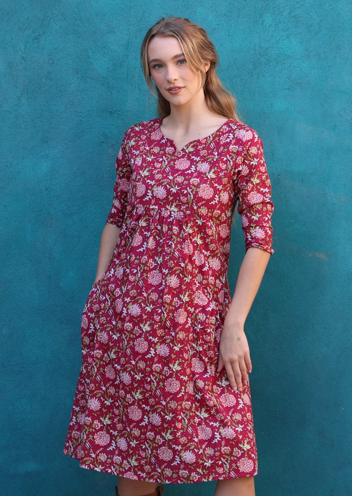 Model is wearing a gorgeous knee length cotton dress with pink florals, round neckline, 3/4 sleeves and pockets.