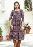 Model standing in 3/4 sleeved cotton dress with pockets, empire waist and round neckline.