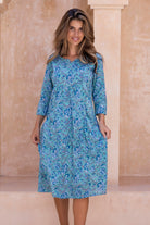 Woman wearing a aqua blue floral cotton dress with sleeves and lining