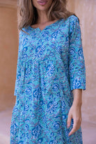 close up of Woman wearing a aqua blue floral cotton dress with sleeves and lining