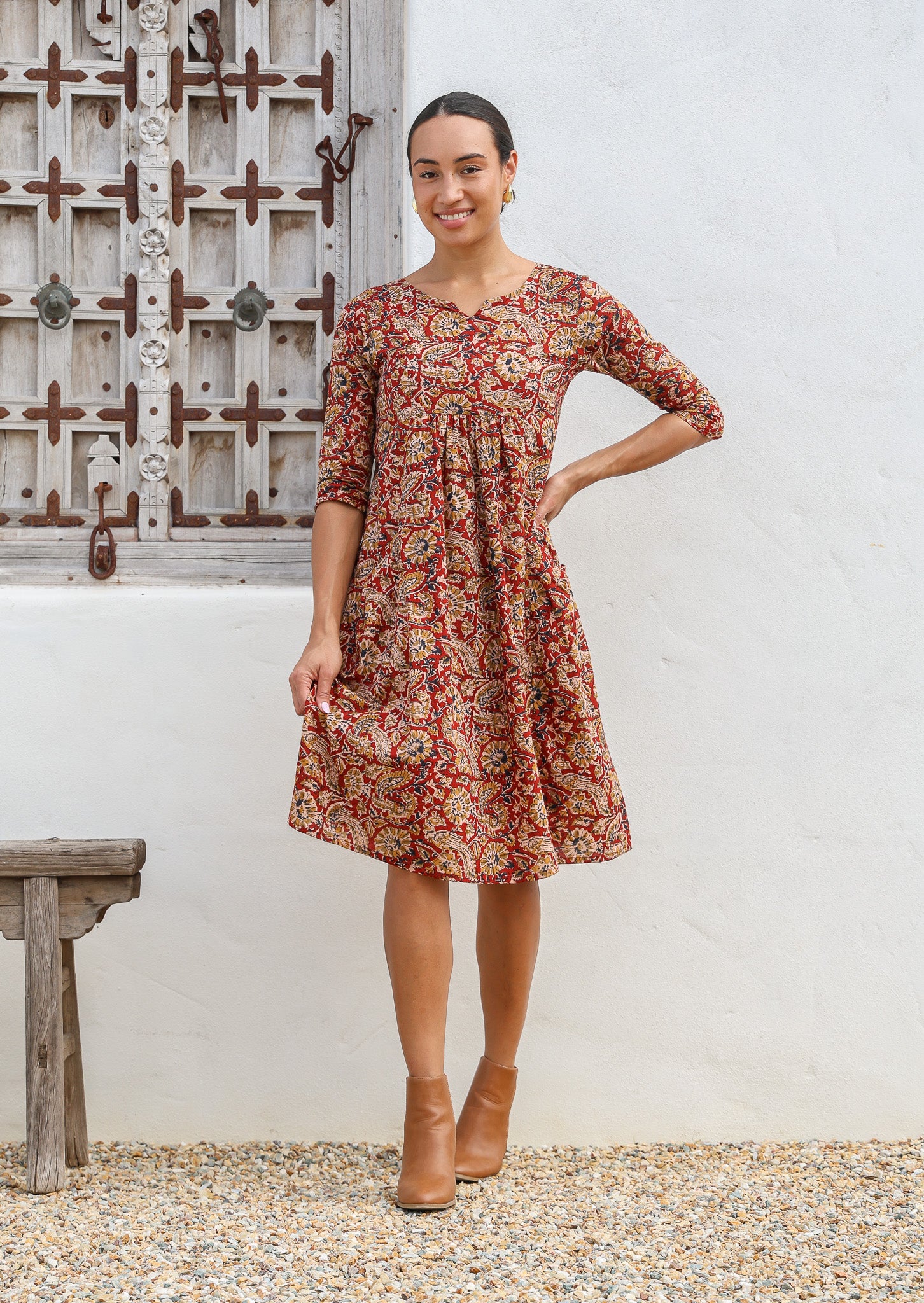 Model is wearing a gorgeous knee length cotton dress with earthy warm florals, round neckline, 3/4 sleeves and pockets.