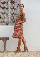 Model posing on sides wears 100% cotton floral printed dress with 3/4 sleeves and hand in pocket.
