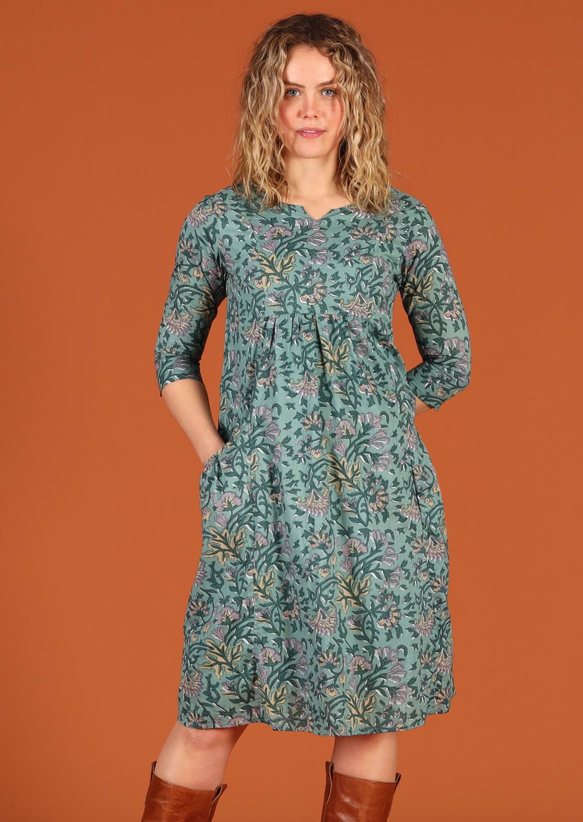 Model in front of orange background wears 100% cotton dress with 3/4 sleeve keyhole cutout neckline.