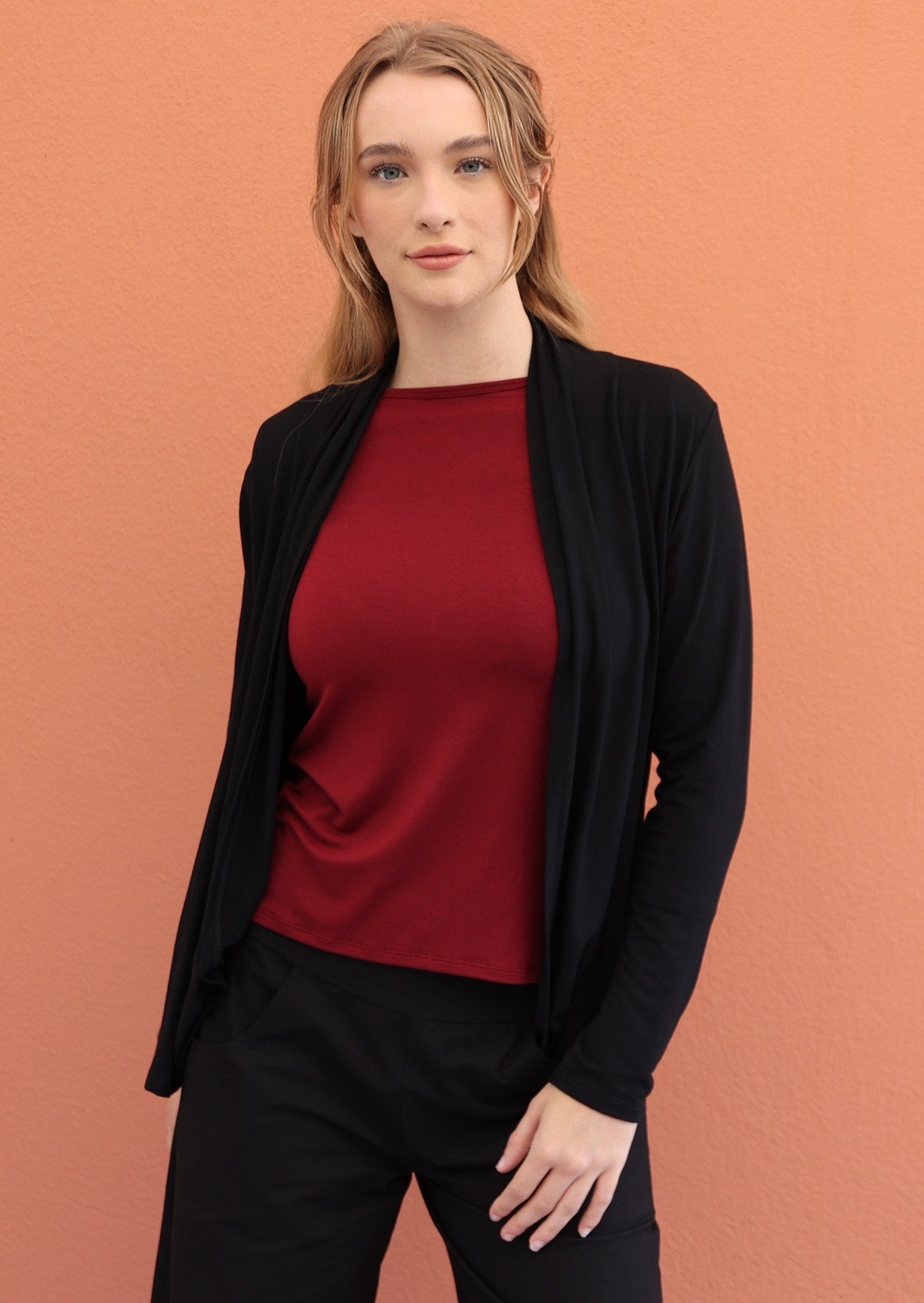 Model wears black soft, stretch rayon cardi with long sleeves, open at front to reveal a maroon top underneath