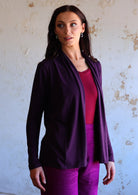 Model in long sleeve dark purple cardi paired beautifully with purple pants and maroon top underneath