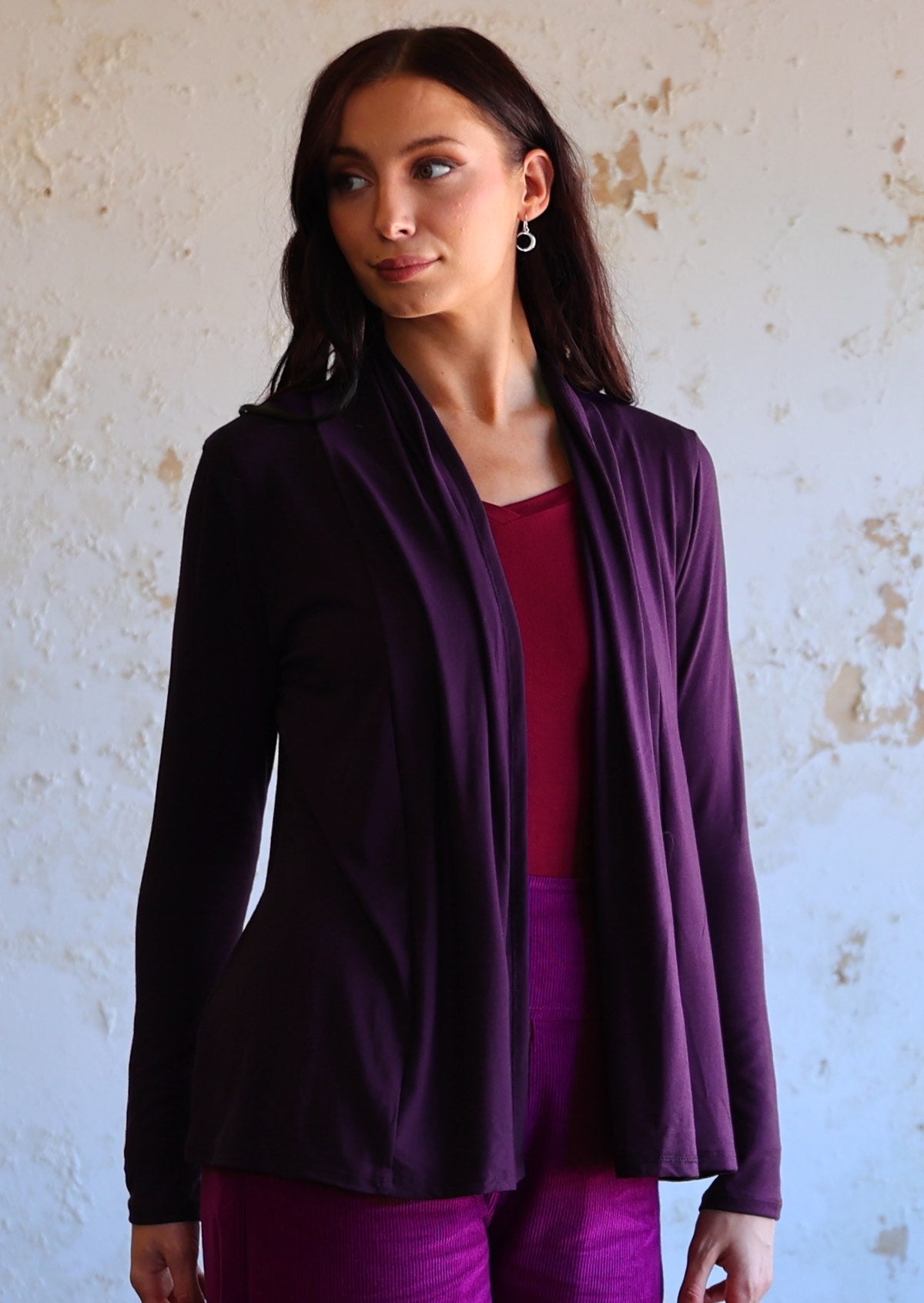 Model wears soft, stretch rayon cardi in dark purple with long sleeves, open at front.