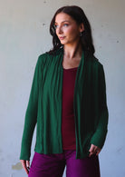Woman poses in green soft, stretch rayon cardi with long sleeves and open neck.