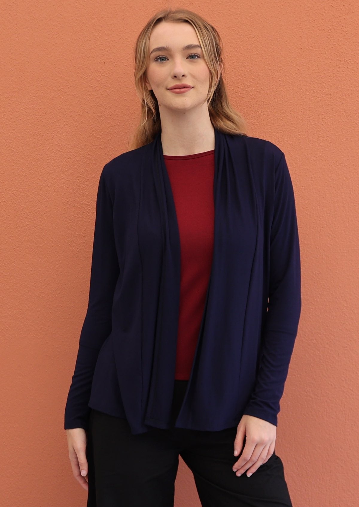 Woman wears navy blue soft, stretch rayon cardi with long sleeves, open front reveals a maroon top.