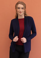 Model wears soft, stretch rayon cardi in navy blue with long sleeves, and holding both front hems.