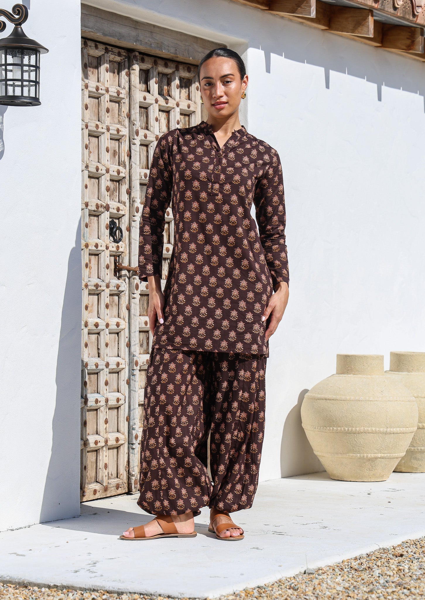 Model wears long sleeve cotton tunic with V-neckline, buttons and mandarin collar, in dark brown floral print.