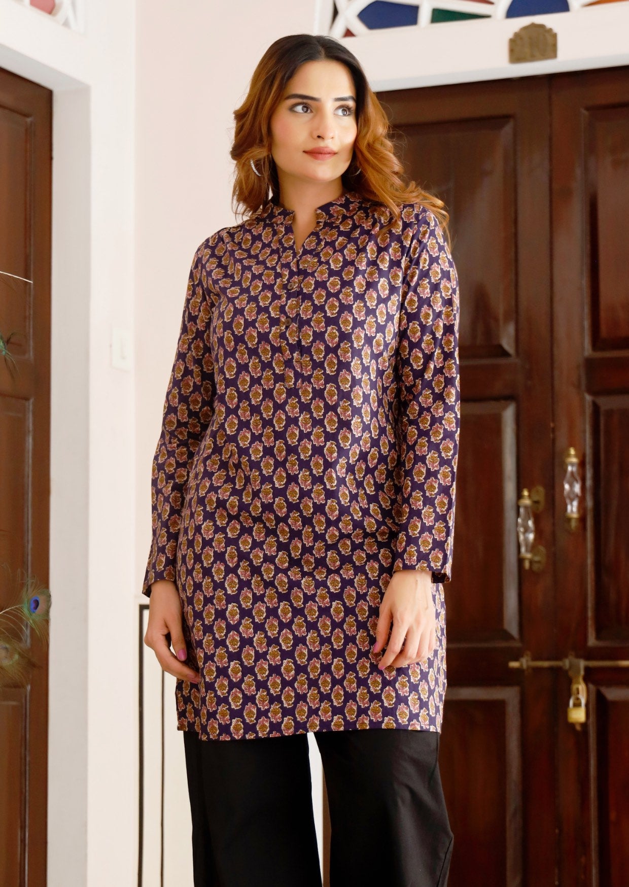 Model wears long sleeve cotton tunic with V-neckline, buttons and a mandarin collar, in purple based floral print