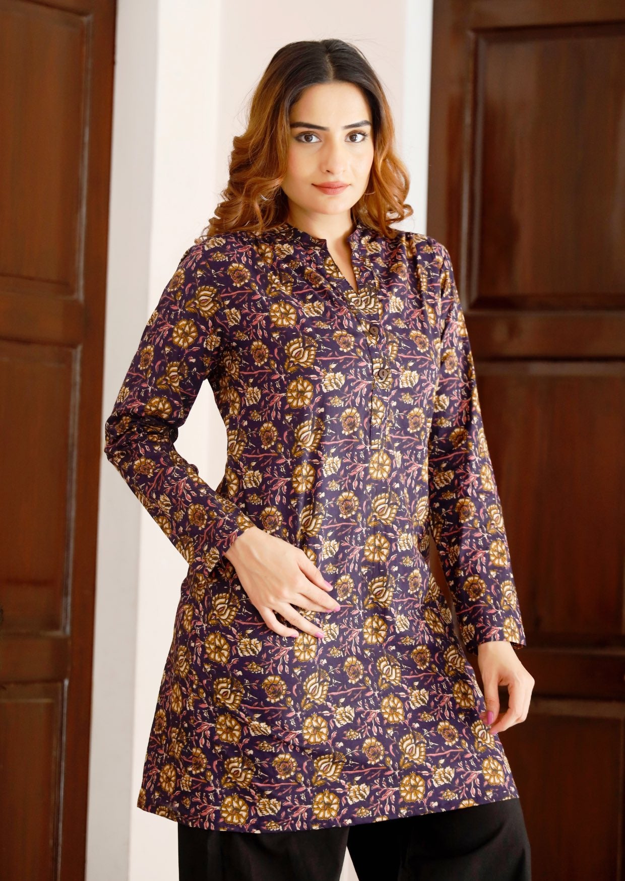 Woman wears lightweight, long cotton tunic with full sleeves in dark purple based floral print.