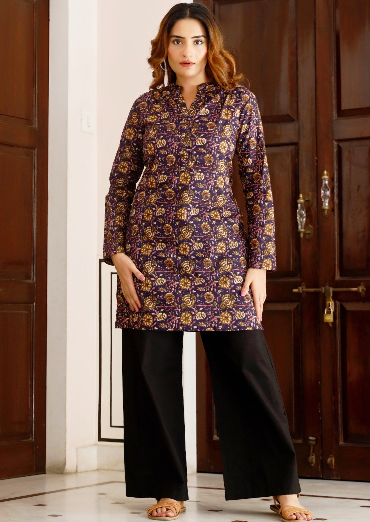 Model poses in long sleeve cotton tunic with V-neckline, buttons and mandarin collar, in purple based floral print.