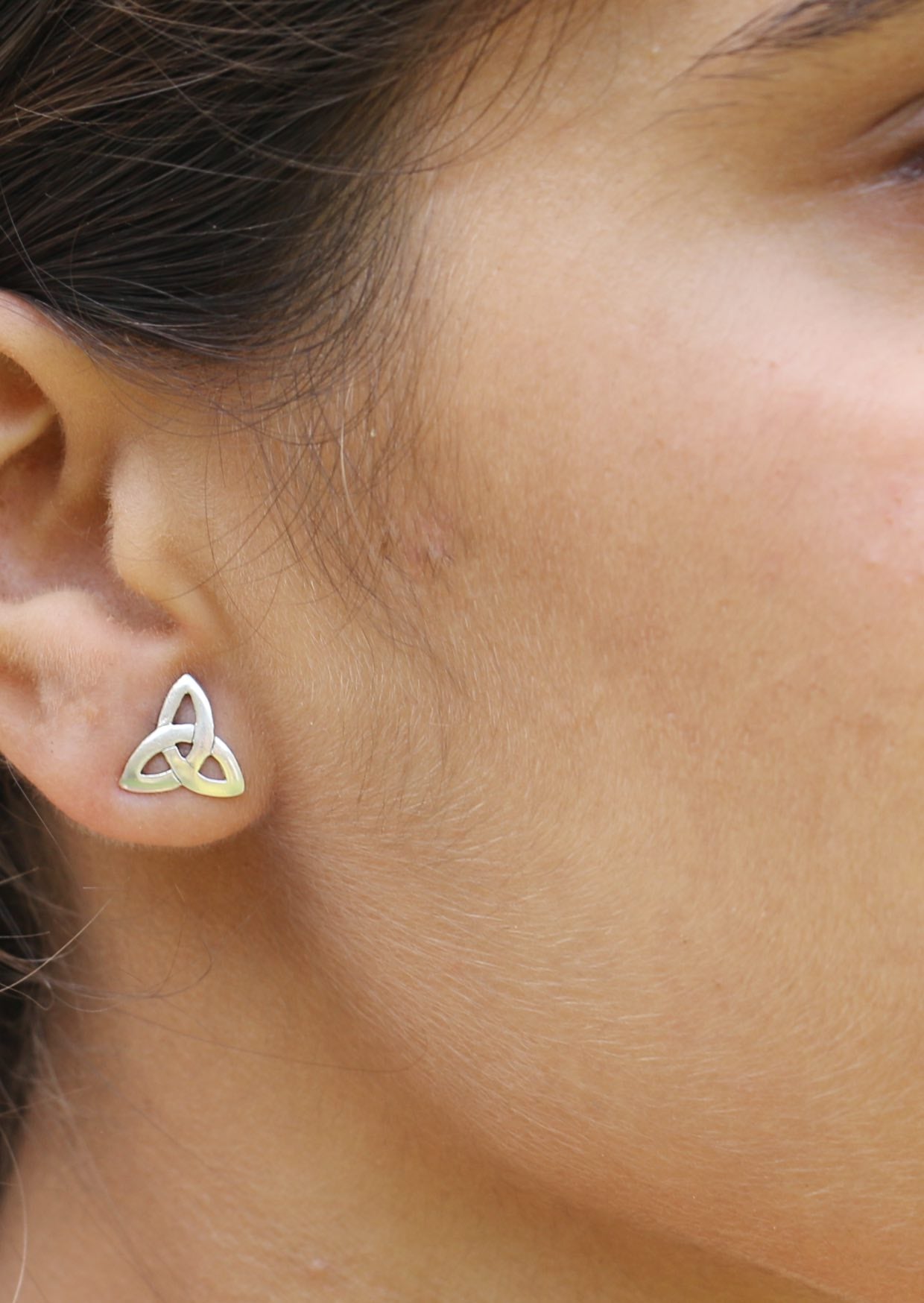 Close-up of an ear wearing a sterling silver Trinity knot stud with butterfly backk