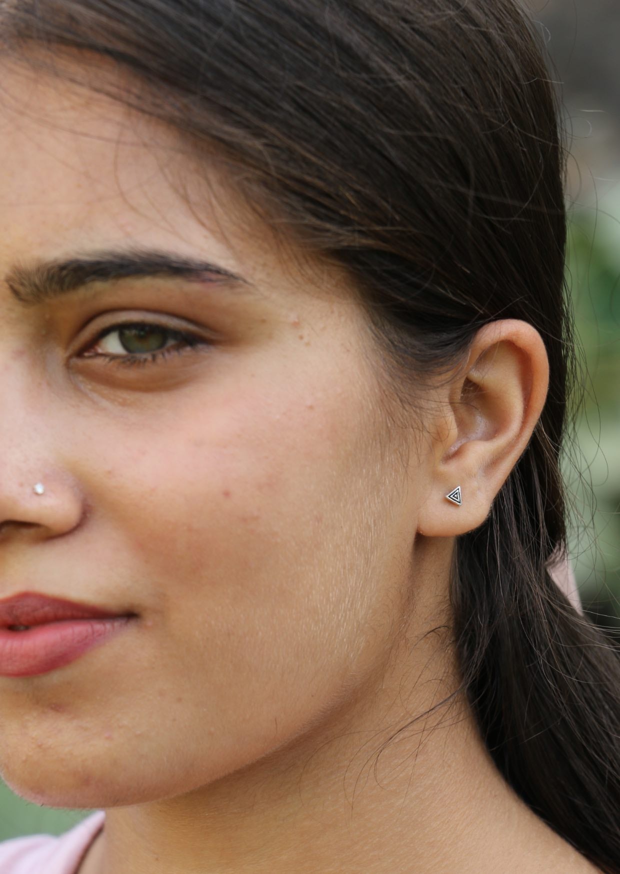 Close-up of a woman wearing a triangle shaped studs with ripple design and secure butterfly backs
