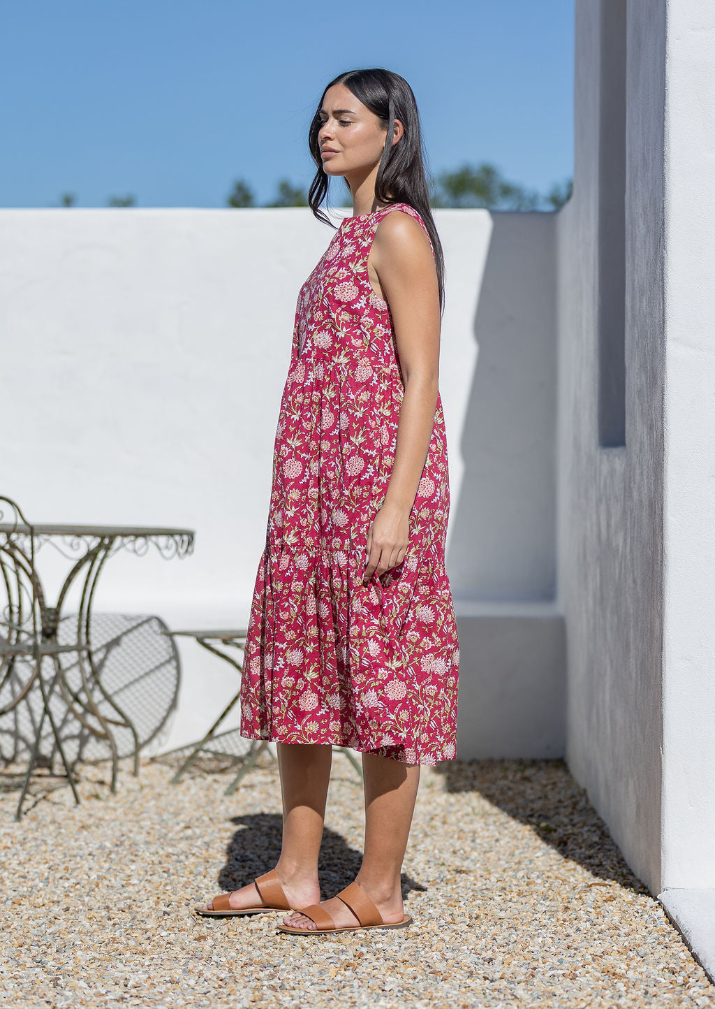 Woman wearing a pink floral cotton midi dress standing outdoors on a sunny day.