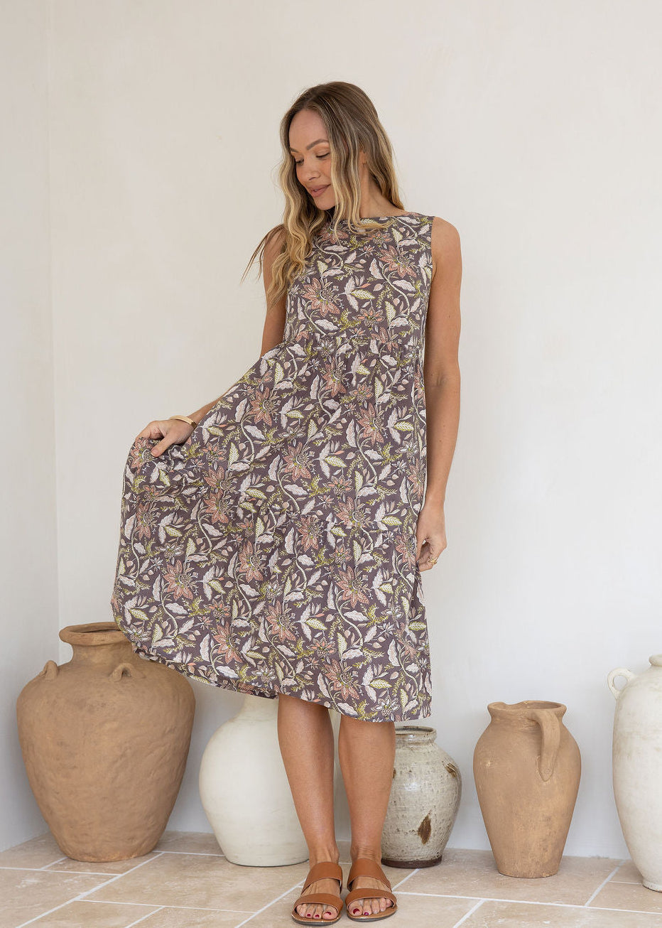 Woman flaunts 100 percent cotton relaxed fit sleeveless dress with high round neckline, pockets and tiered style.