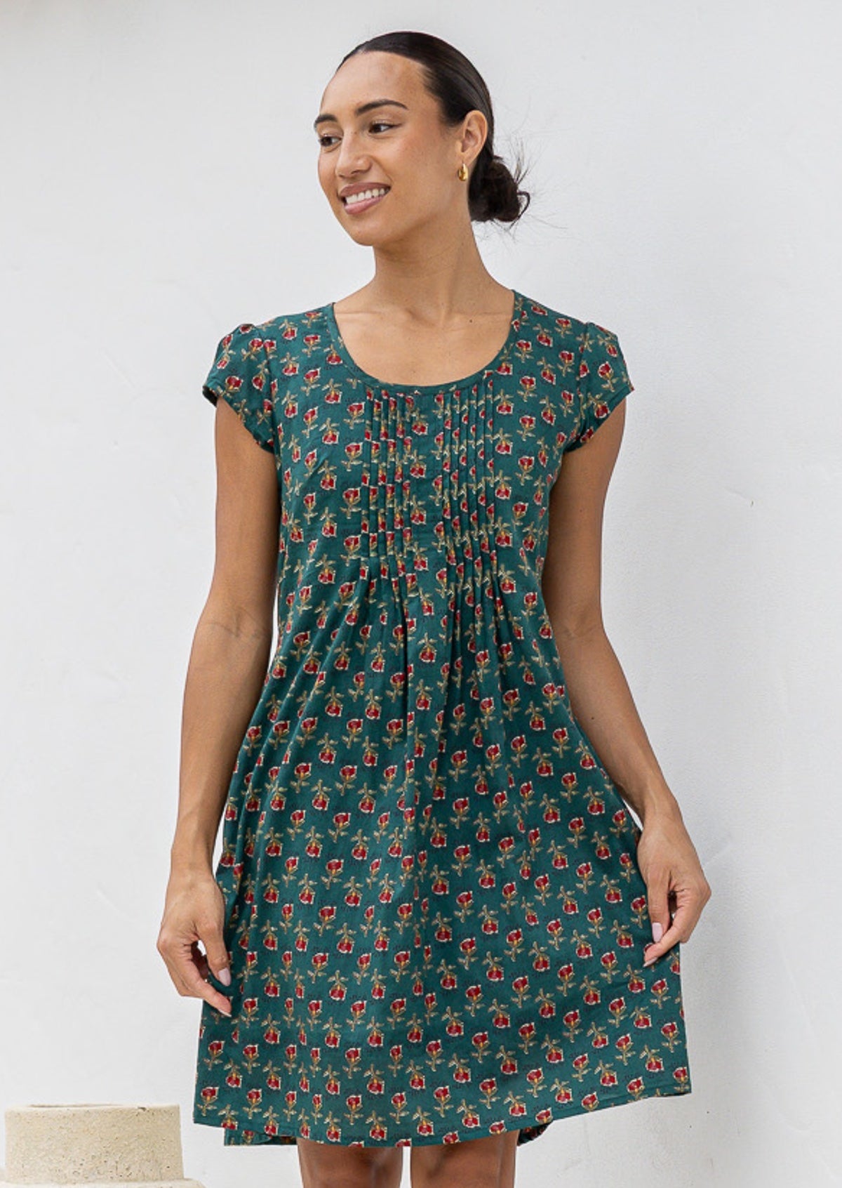 Woman wearing a green floral cotton dress against a white background