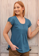 Smiling model wears a short sleeve top with cap sleeves that have a small elastic trim.