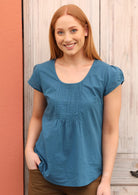 Model wears a short sleeve top with small decorative pleats on the bust.