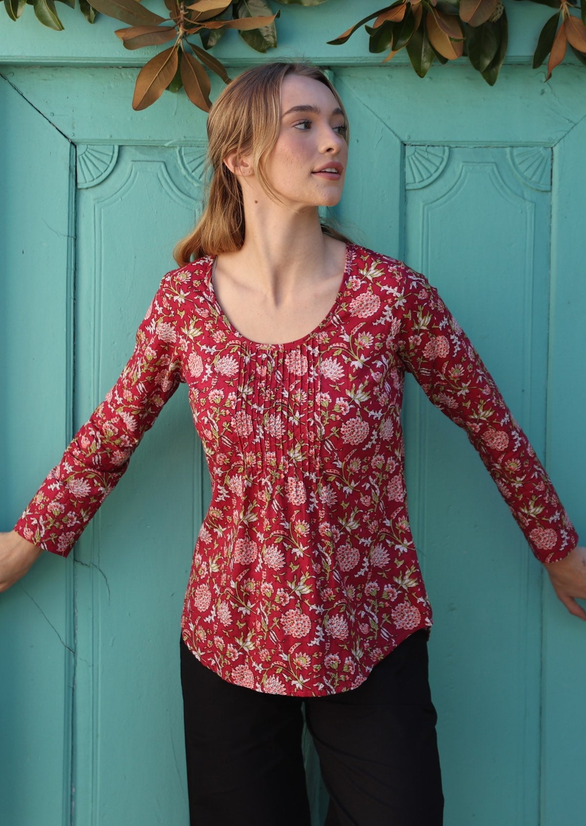 Model wearing a flattering long sleeve top with beautiful red base and pink, white florals.