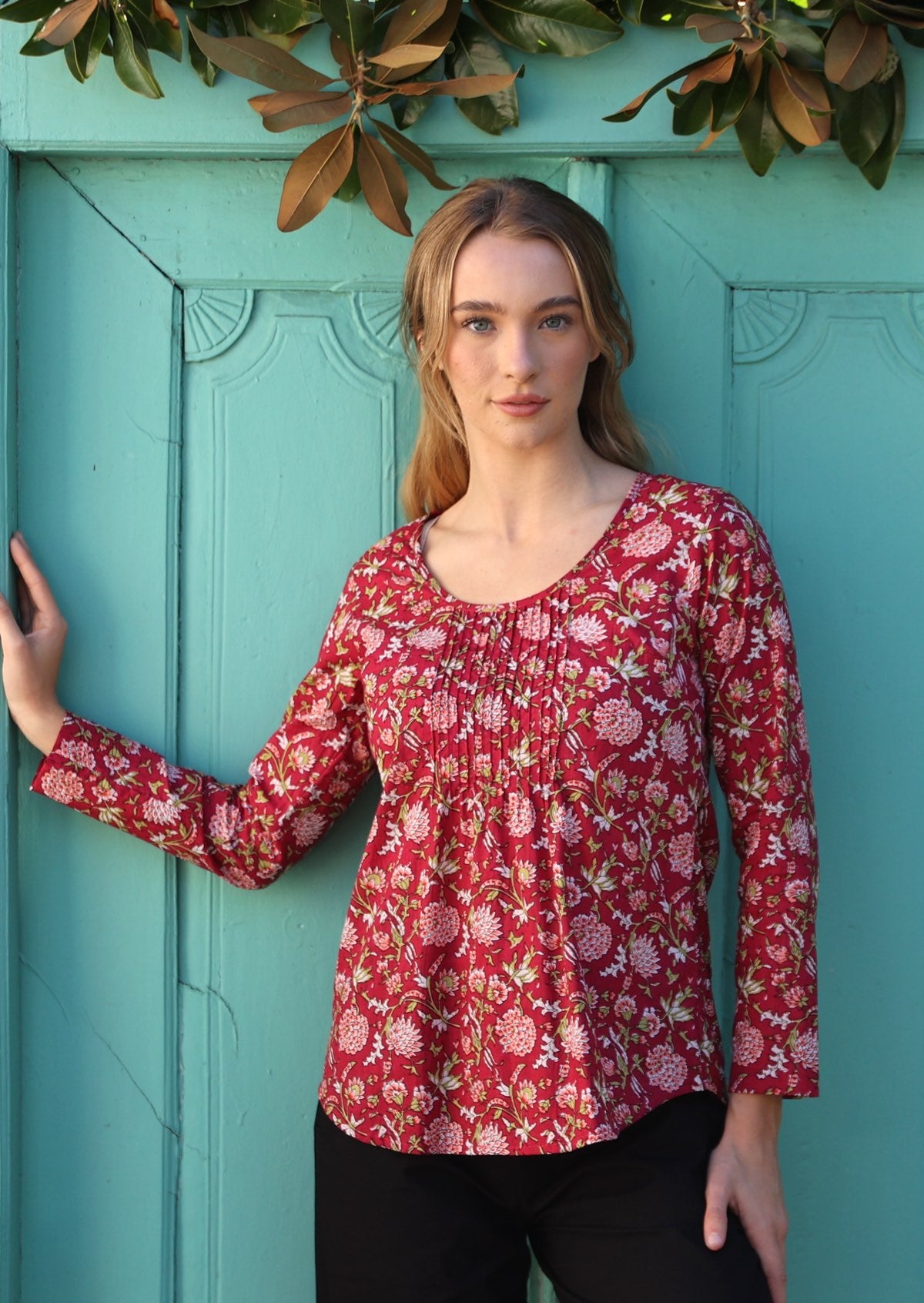 Model wearing 100% cotton long sleeve top with round neckline and tiny pleat detail from the center of the neckline.