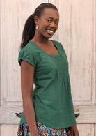 Model wears a 100% cotton top with cap sleeves.
