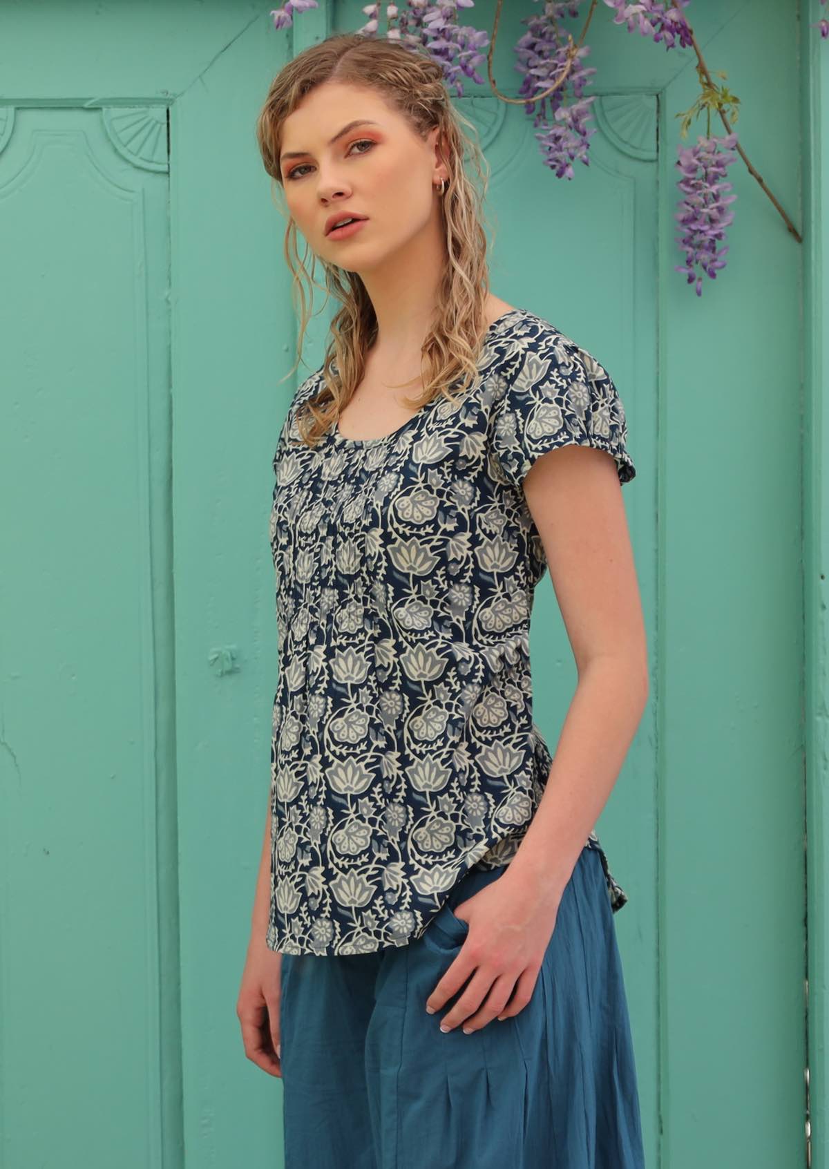 Model wears a cotton top with a round neckline and decorative pleats.