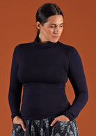 Woman wearing a turtle neck navy blue fitted long sleeve soft stretch rayon top.