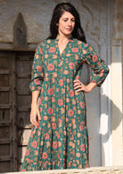 Model wears dark green based floral cotton dress with pockets, 3/4 sleeves and V neckline.
